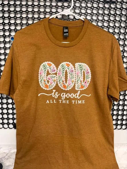Mustard gold T-shirt with floral ‘God is good all the time’ lettering.